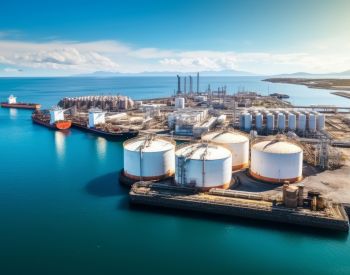 Aerial view of an industrial port with large cylindrical storage tanks.